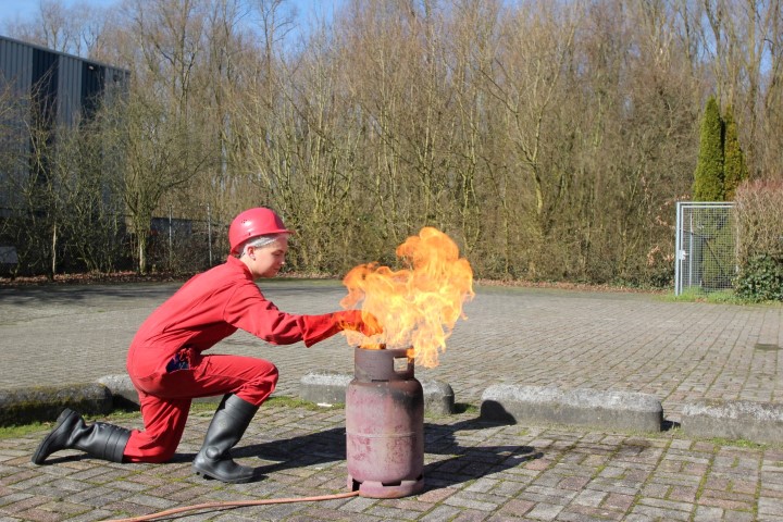 Cursist blust gecontroleerd een oefenvuur met blusser